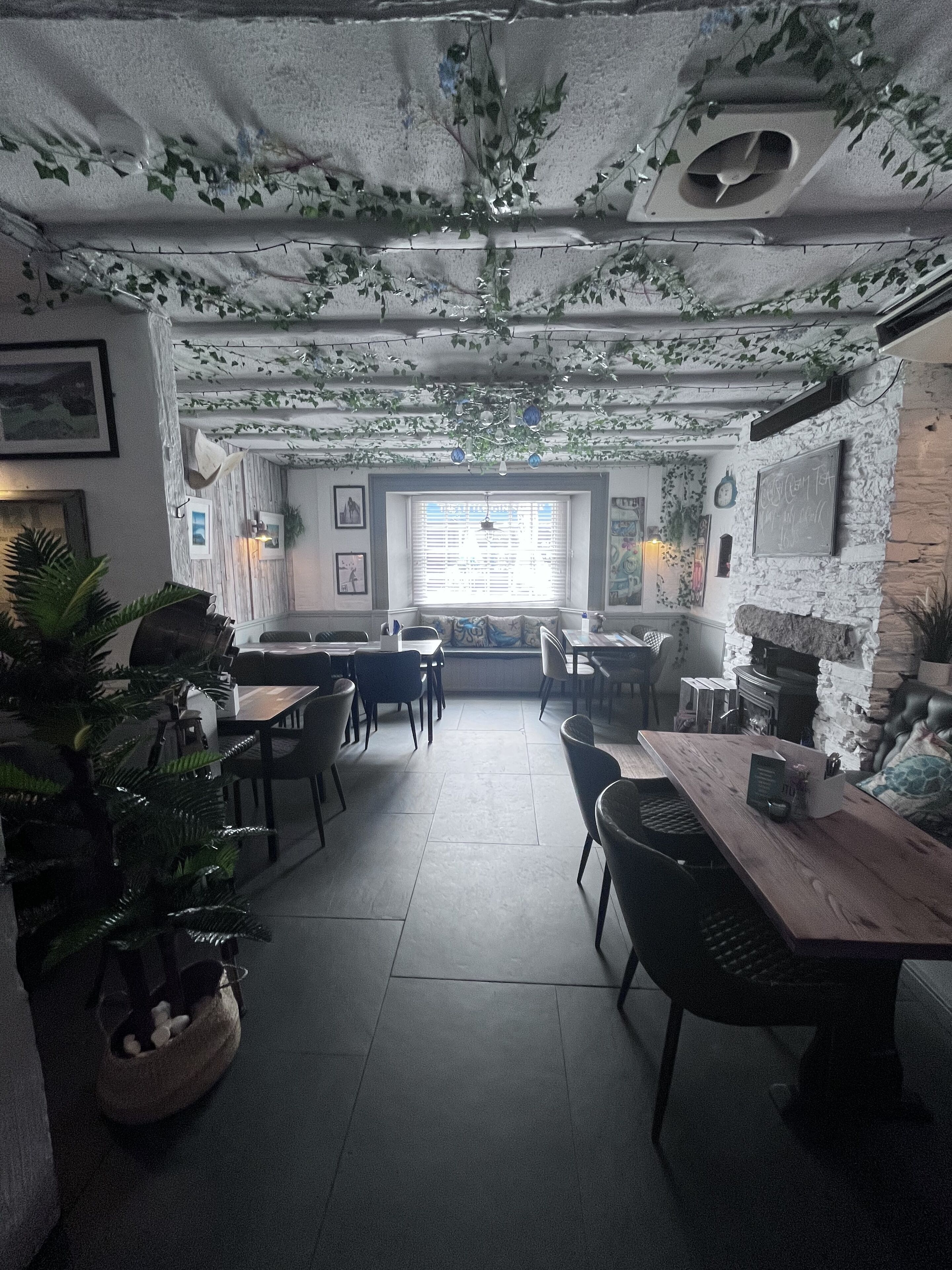 A cozy restaurant interior with a rustic stone wall, wooden tables, and chairs.