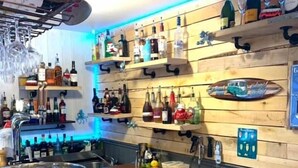 Eine Bar mit Regalen voller Spirituosenflaschen, einer großen Rührschüssel und einer Holztresenplatte mit Schneidebrett und Zitronen.