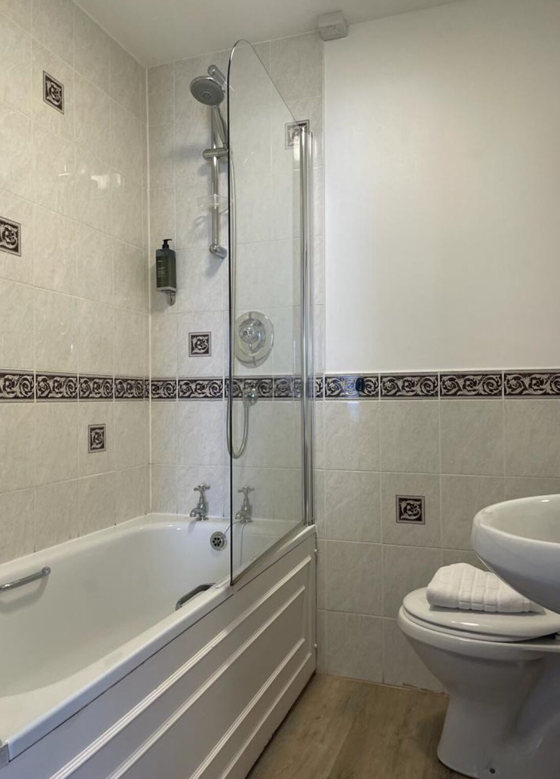 A bathroom with a glass-enclosed shower, a white bathtub, and a toilet.