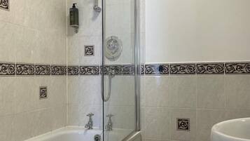 A bathroom with a glass-enclosed shower, a white bathtub, and a toilet.