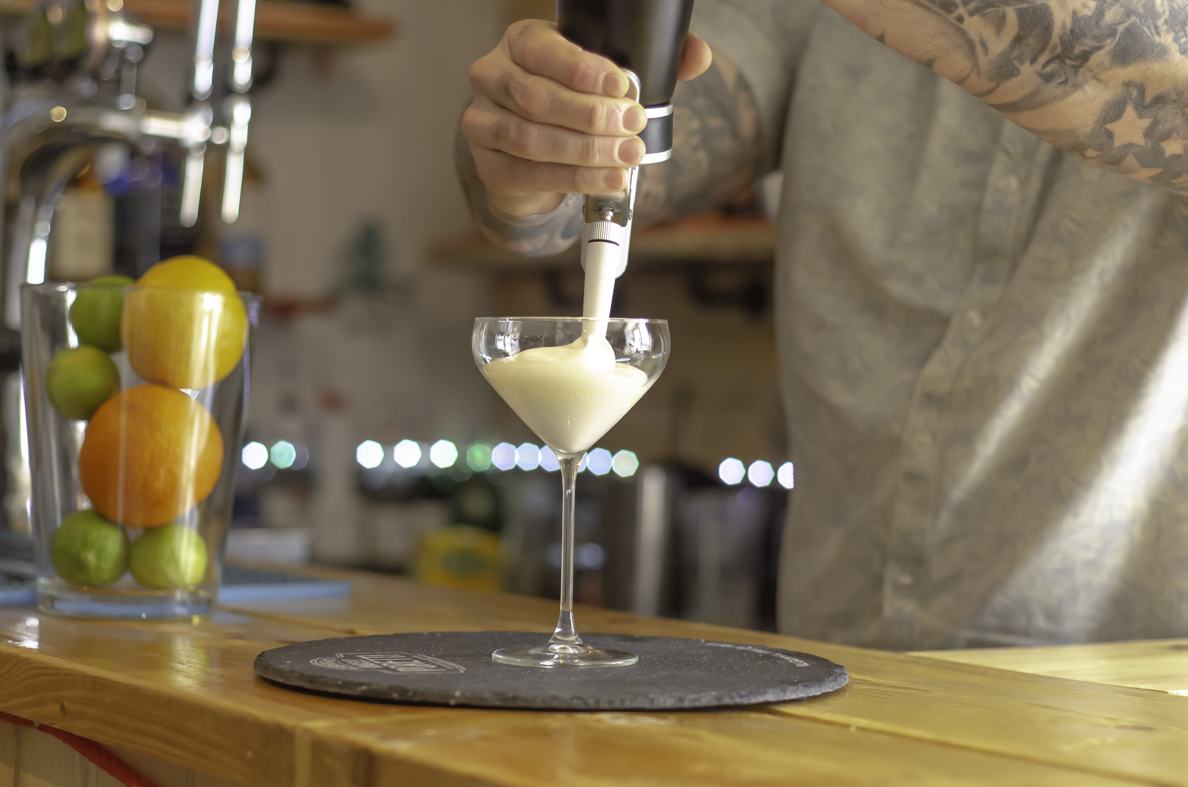 A person pouring a creamy liquid into a martini glass.