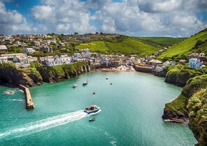 A coastal town with a harbor, boats, and houses along the cliffs. - Molesworth Arms (Wadebridge)