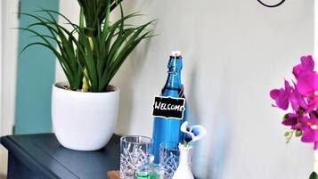 Una mesa azul oscuro con una botella, vasos y una pequeña planta.