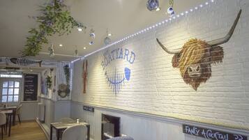 L’intérieur d’un restaurant avec un mur en briques blanches, une décoration représentant une tête de lion et une enseigne indiquant « The Boatyard ».