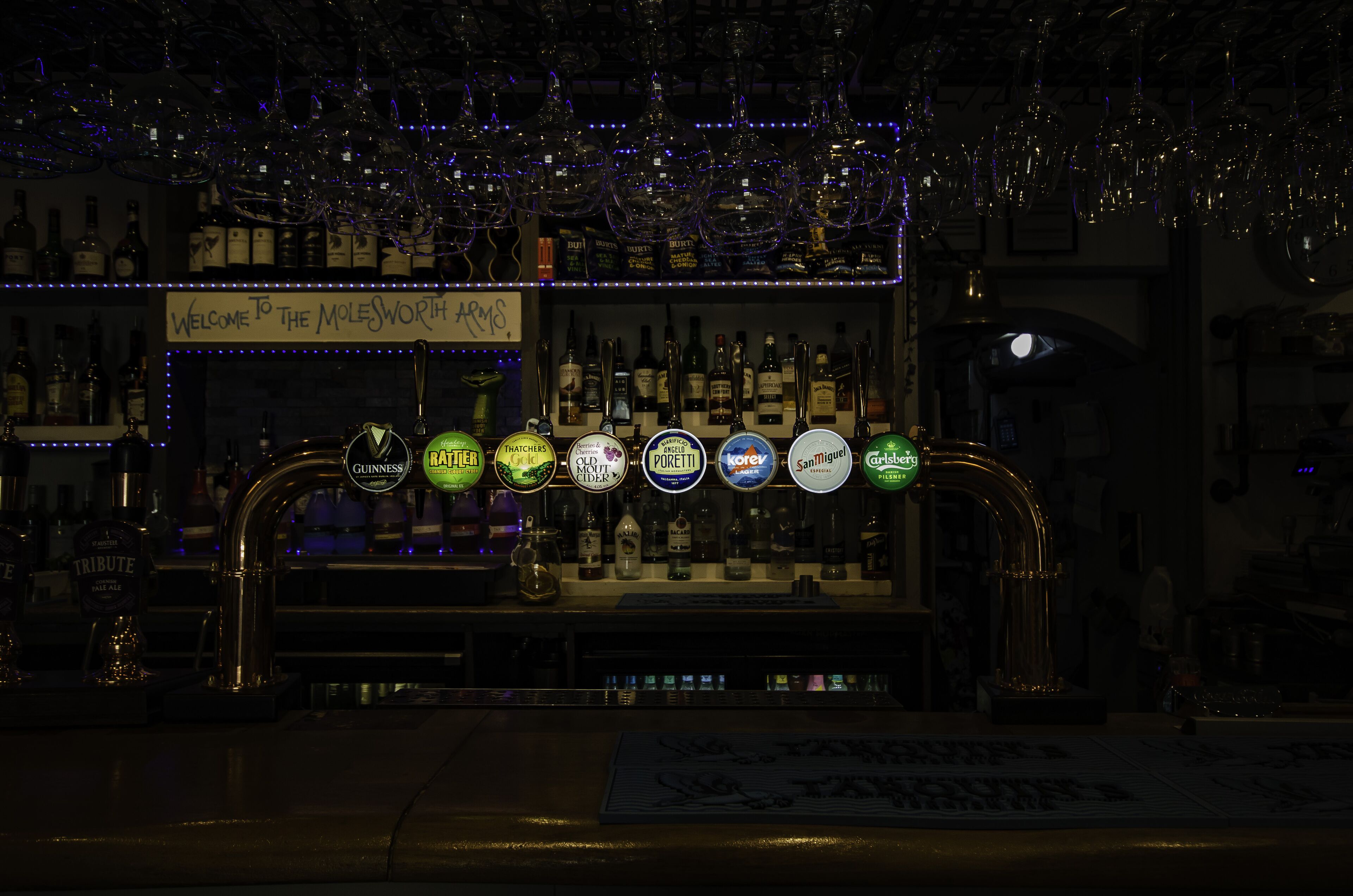 A bar with a variety of liquor bottles and a selection of beer taps.