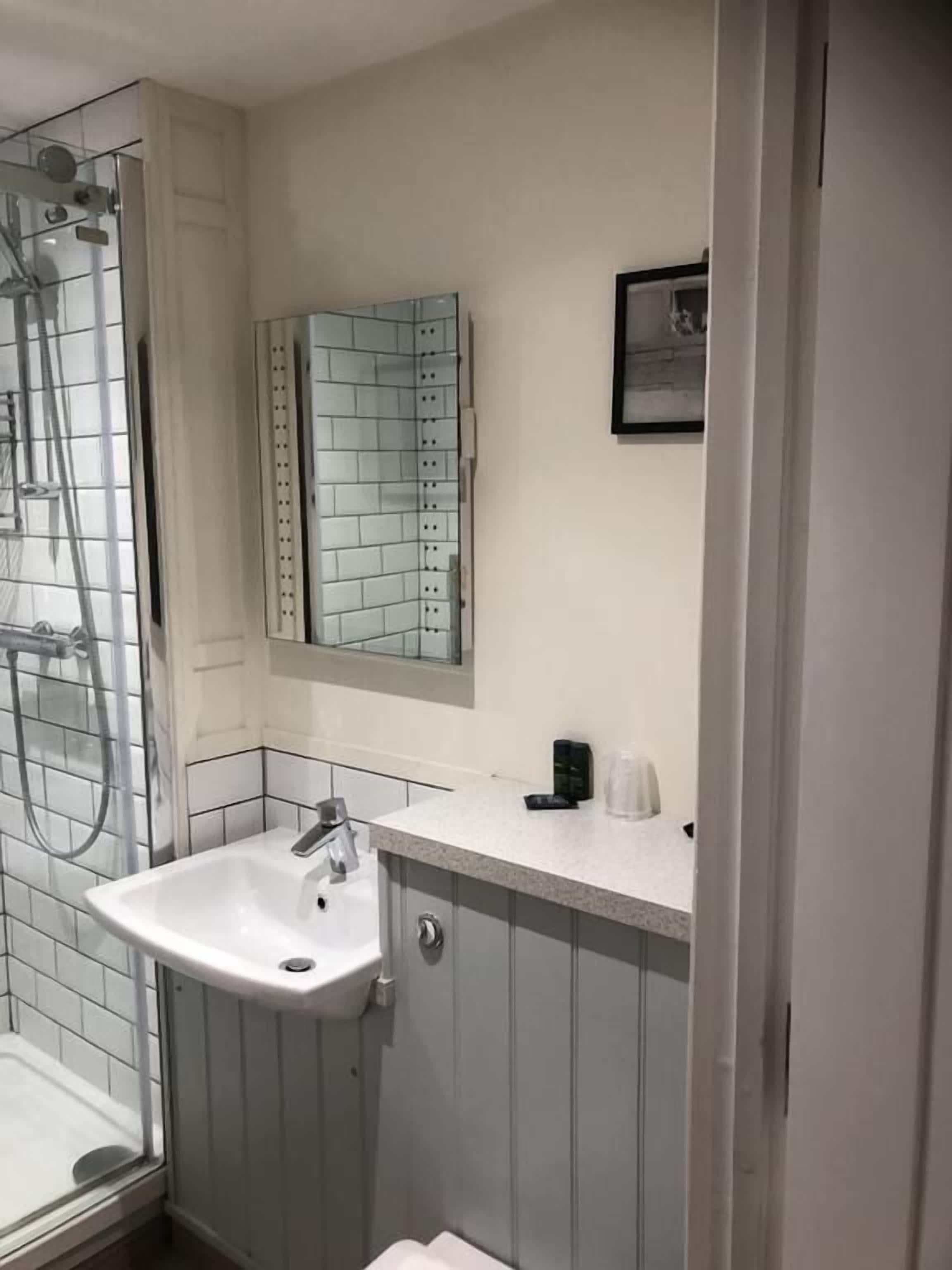 A bathroom with a shower, a sink, and a mirror.