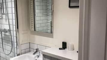 A bathroom with a shower, a sink, and a mirror.