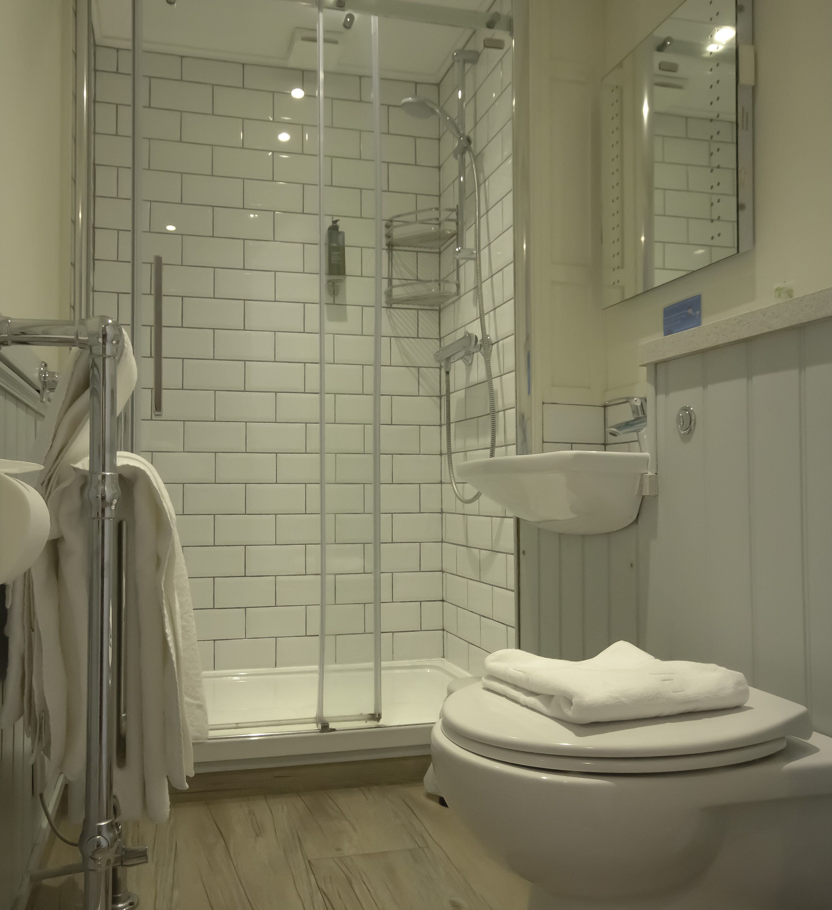 Une salle de bain avec une douche à parois de verre, un lavabo blanc et des toilettes.