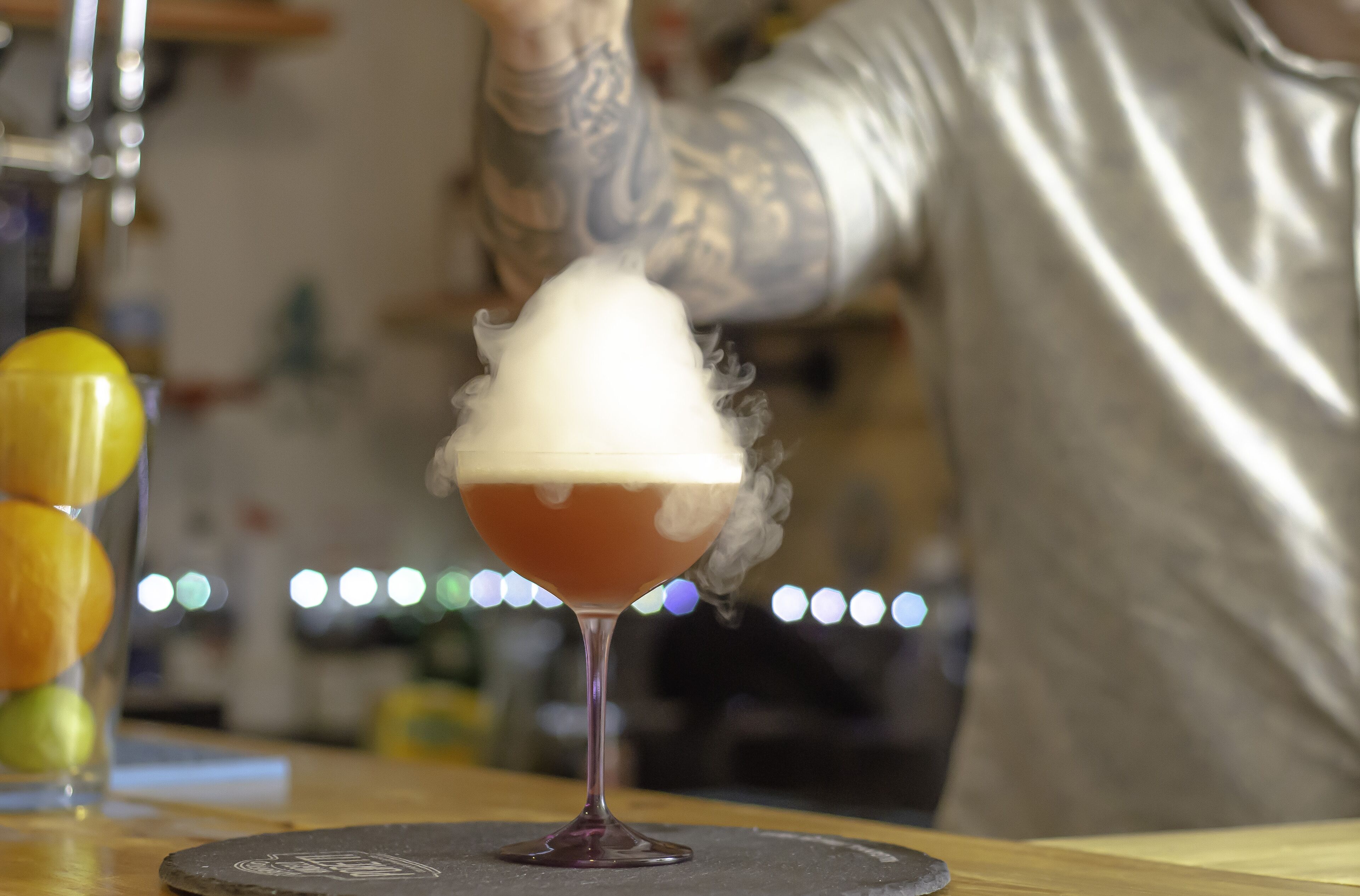 A cocktail with a foamy top in a glass on a coaster.