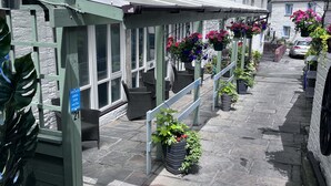 Ein Hotel mit Eingangsbereich, überdachter Terrasse und hängenden Blumentöpfen.
