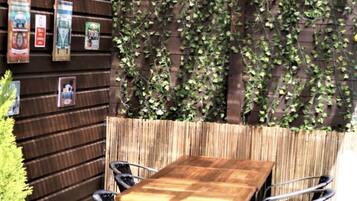 A wooden table with four chairs in a garden area with a wooden fence and greenery.