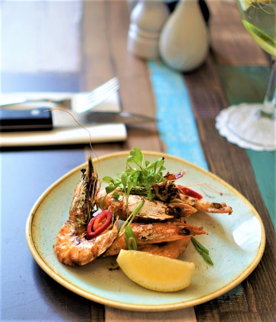 Un plato de pescado a la parrilla con limón y hierbas, sobre un plato de cerámica.
