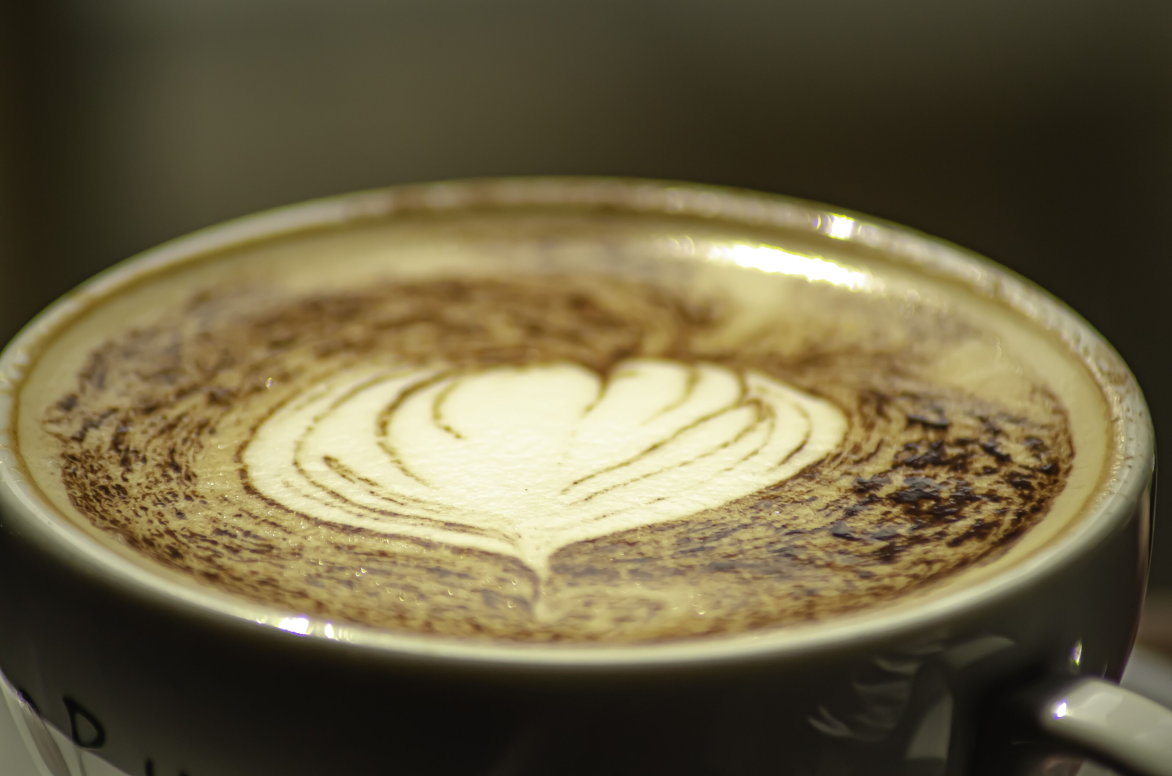 A close-up of a cup of coffee with a latte art design.