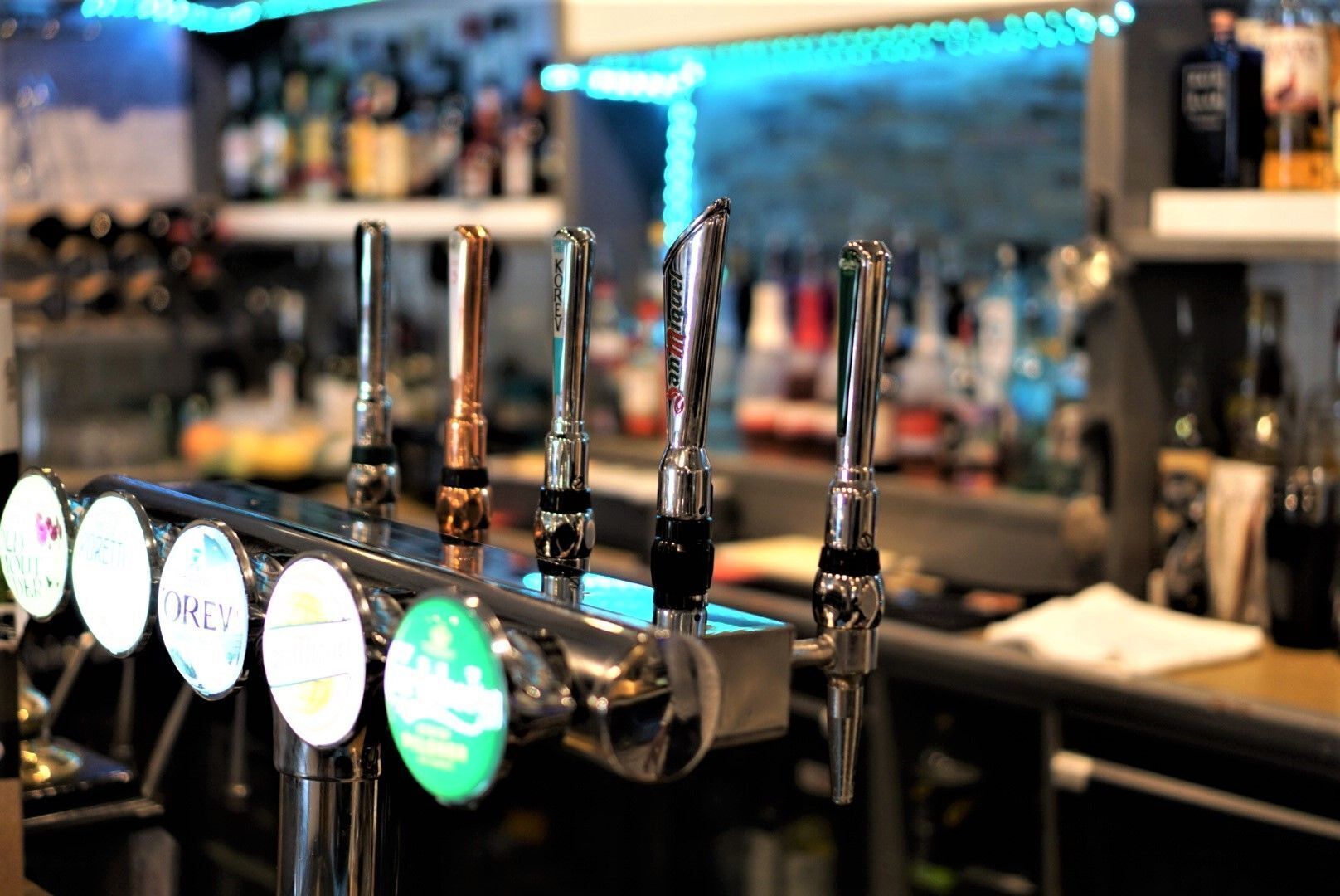 A bar with multiple taps, each labeled with different beer brands.