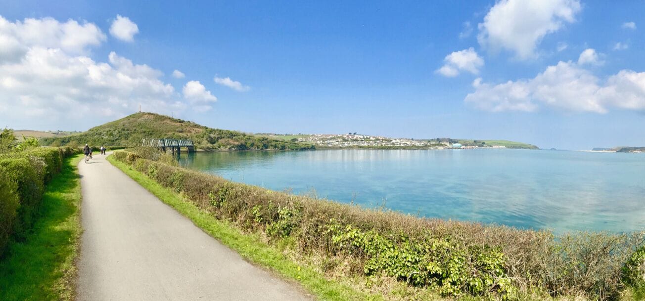 A coastal road with a clear view of the sea and a bridge in the distance.
