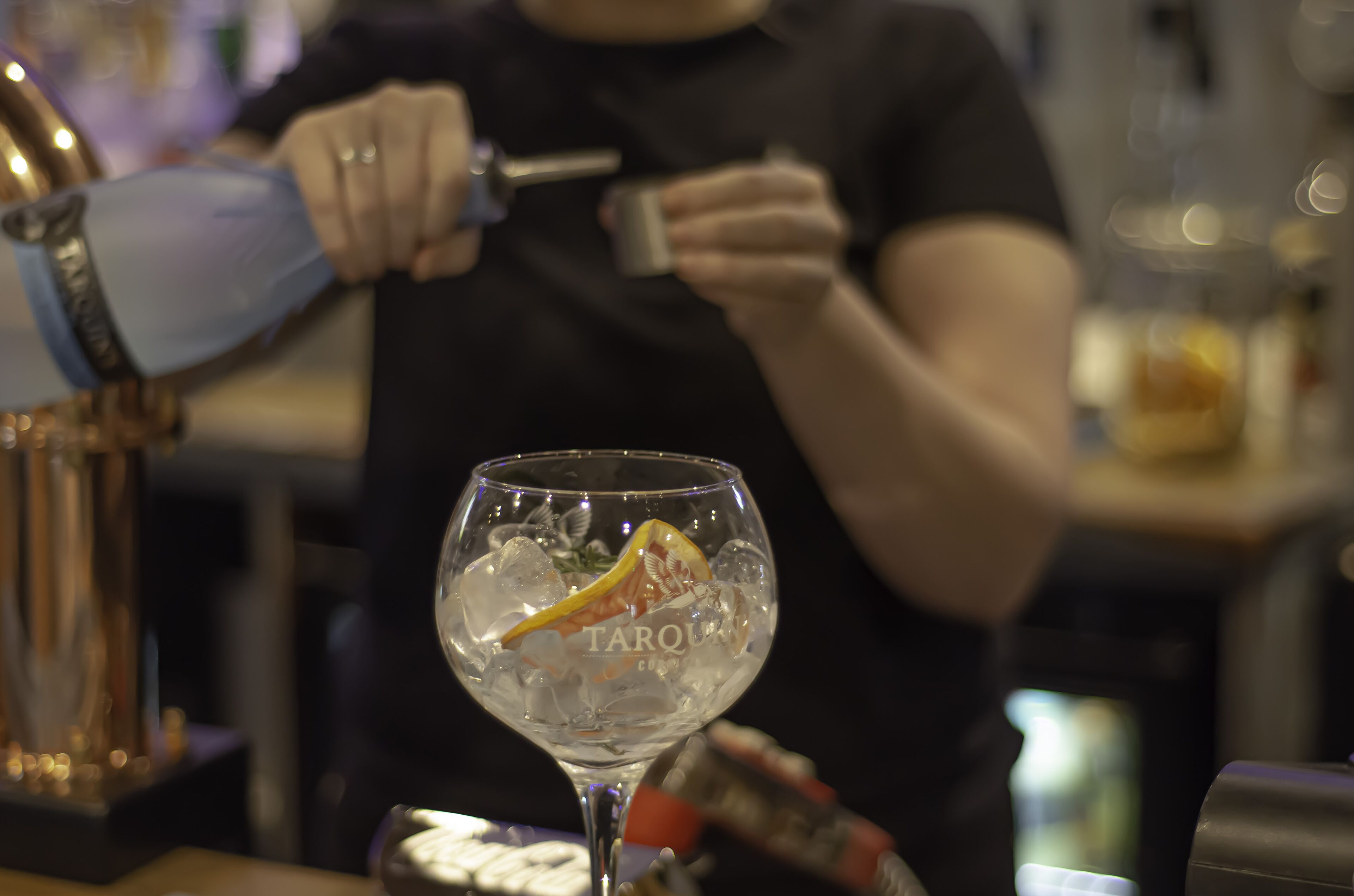 Een barscène, met een glas water en een barman die een drankje bereidt.