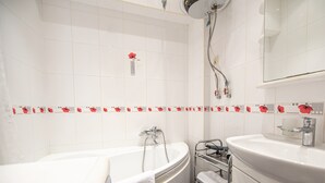 A bathroom with a bathtub, a sink, and a shower. There are towels on a rack and a mirror above the sink. - WINWINSTAY Old Town City Apartment (Riga)
