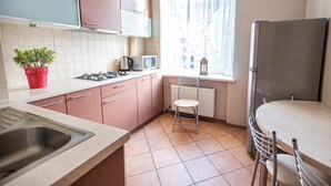 A compact kitchen with a sink, stove, microwave, and a window with curtains. - WINWINSTAY Old Town City Apartment (Riga)