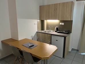 A compact kitchen with a wooden table, a small refrigerator, and a sink. - Acropolis Apartments (Hersonissos)