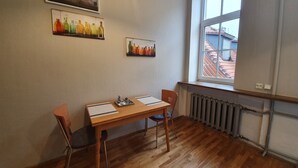 A room with a wooden table and chairs, a radiator, and two paintings on the wall. - WINWINSTAY Old Town Riverside Apartment (Riga)
