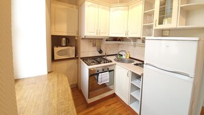 A compact kitchen with white cabinets, a gas stove, a microwave, and a refrigerator. - WINWINSTAY Old Town Riverside Apartment (Riga)