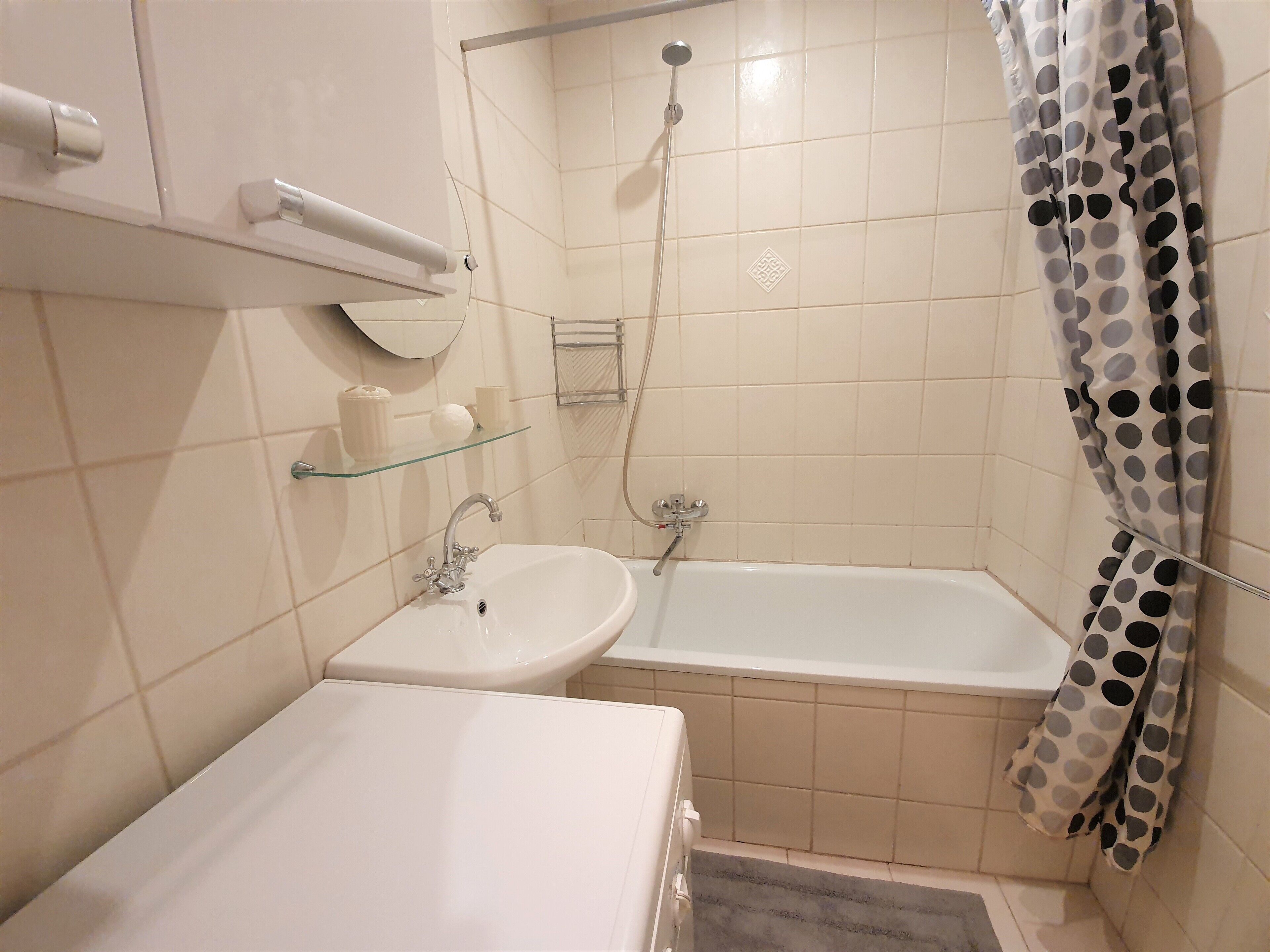 Un baño con lavamanos, espejo y ducha.