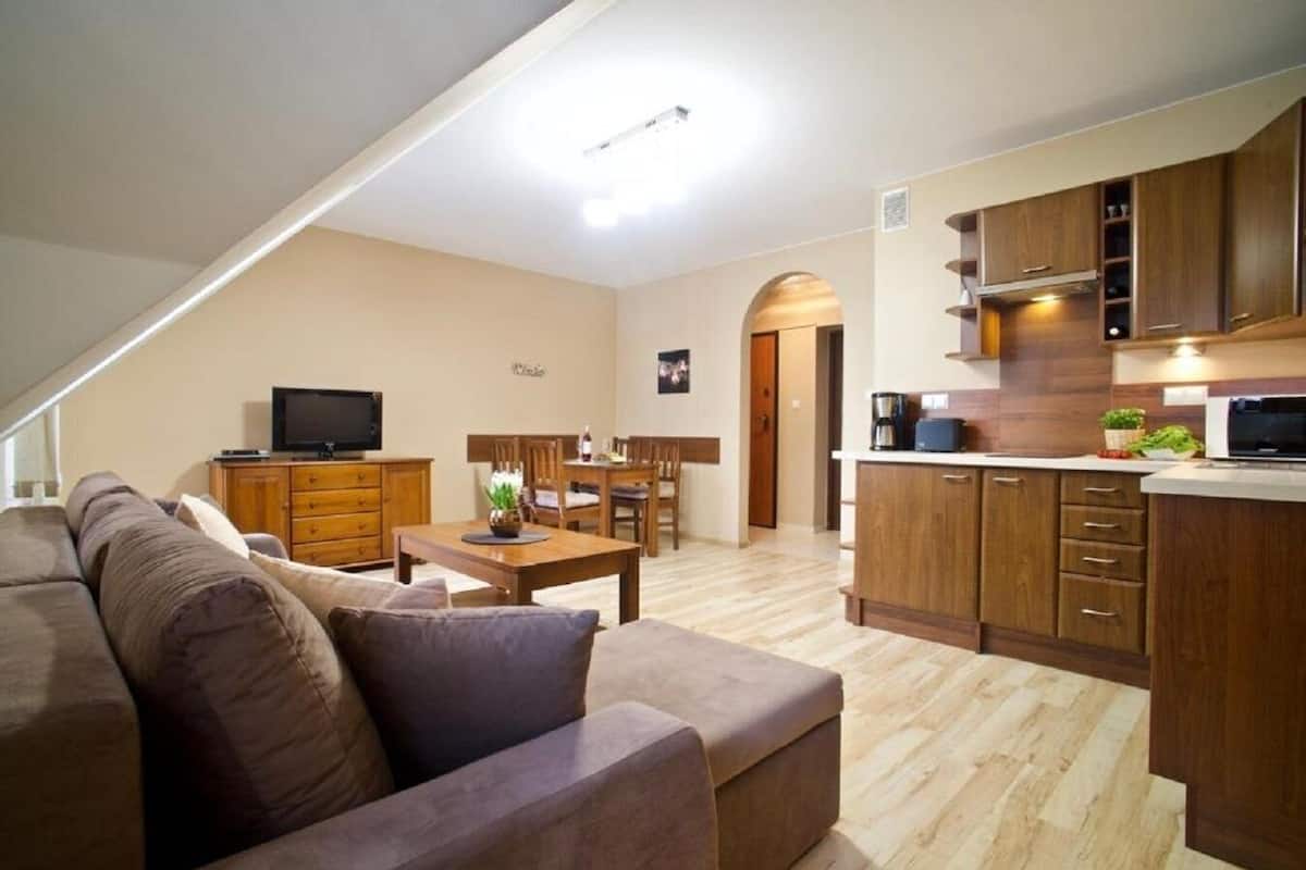 A modern apartment with a living room, dining area, and kitchen.