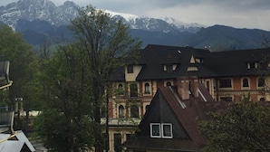 Un bâtiment traditionnel doté d’un toit en pente, d’un balcon et offrant une vue sur des montagnes enneigées.