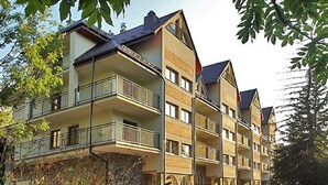 Un hôtel à plusieurs étages, doté de balcons, d’une façade en pierre et d’un chemin menant à l’entrée.