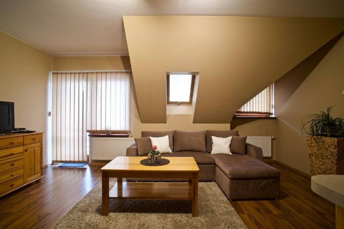 A cozy living room with a wooden coffee table, brown sofa, and a television on a wooden cabinet.