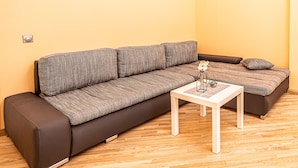 Un salon moderne avec un canapé, une petite table et un luminaire fixé au mur.