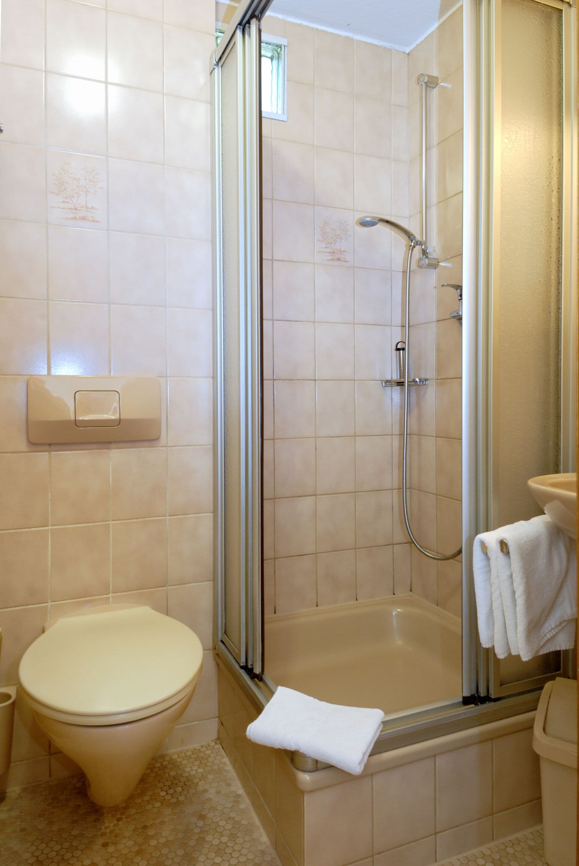 Ein Badezimmer mit Toilette, Duschkabine und Waschbecken mit Handtuch.