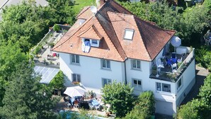 Une maison à deux étages avec un toit en tuiles, un balcon agrémenté de meubles d’extérieur et une piscine.