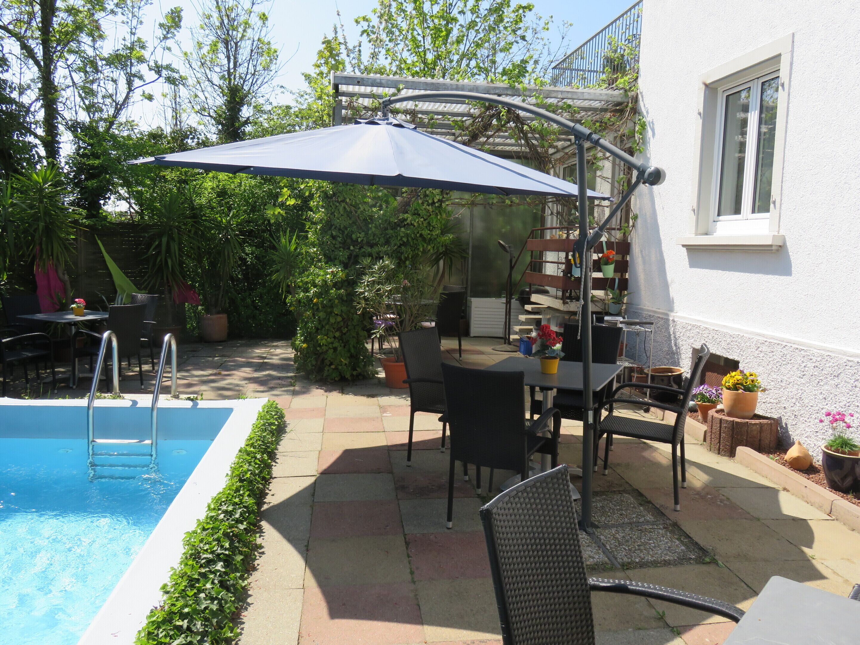Uma área de pátio com piscina, móveis de exterior e um espaço coberto para sentar.