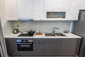 A modern kitchen with white cabinets, a Bosch oven, a built-in microwave, and a stainless steel sink.