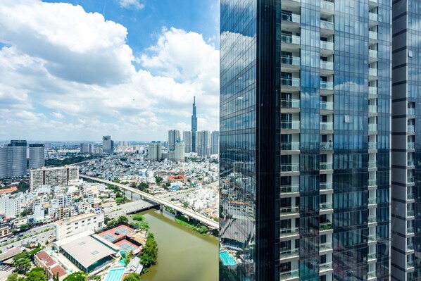 A high-rise building with a glass facade, a river, and a bridge in the background.