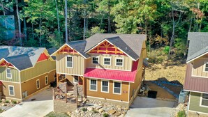 A residential area with multiple houses featuring a mix of siding colors and red roofs, surrounded by trees and a clear sky. - Blue Lagoon Cinema (Gatlinburg)