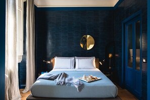 Un dormitorio con una cama grande, un espejo redondo encima y una bandeja con objetos sobre la cama.