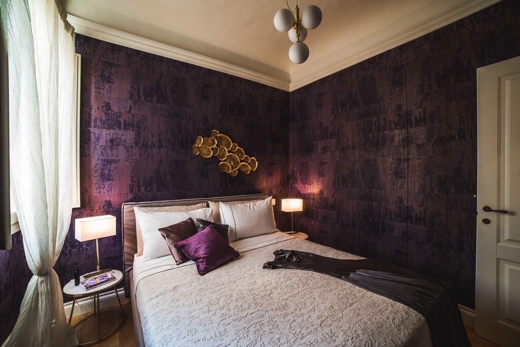 Een hotelkamer met een groot bed, twee nachtkastjes, een wandlamp en een deur.