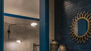 Un intérieur moderne avec un coin repas comprenant une table et des chaises en bois, un mur d’accent bleu et un miroir décoratif en forme de soleil.