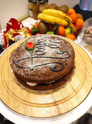 A cake with a Santa hat and the word "Merry" on top, placed on a wooden board. - Palazzo Verdi B&B (Viterbo)