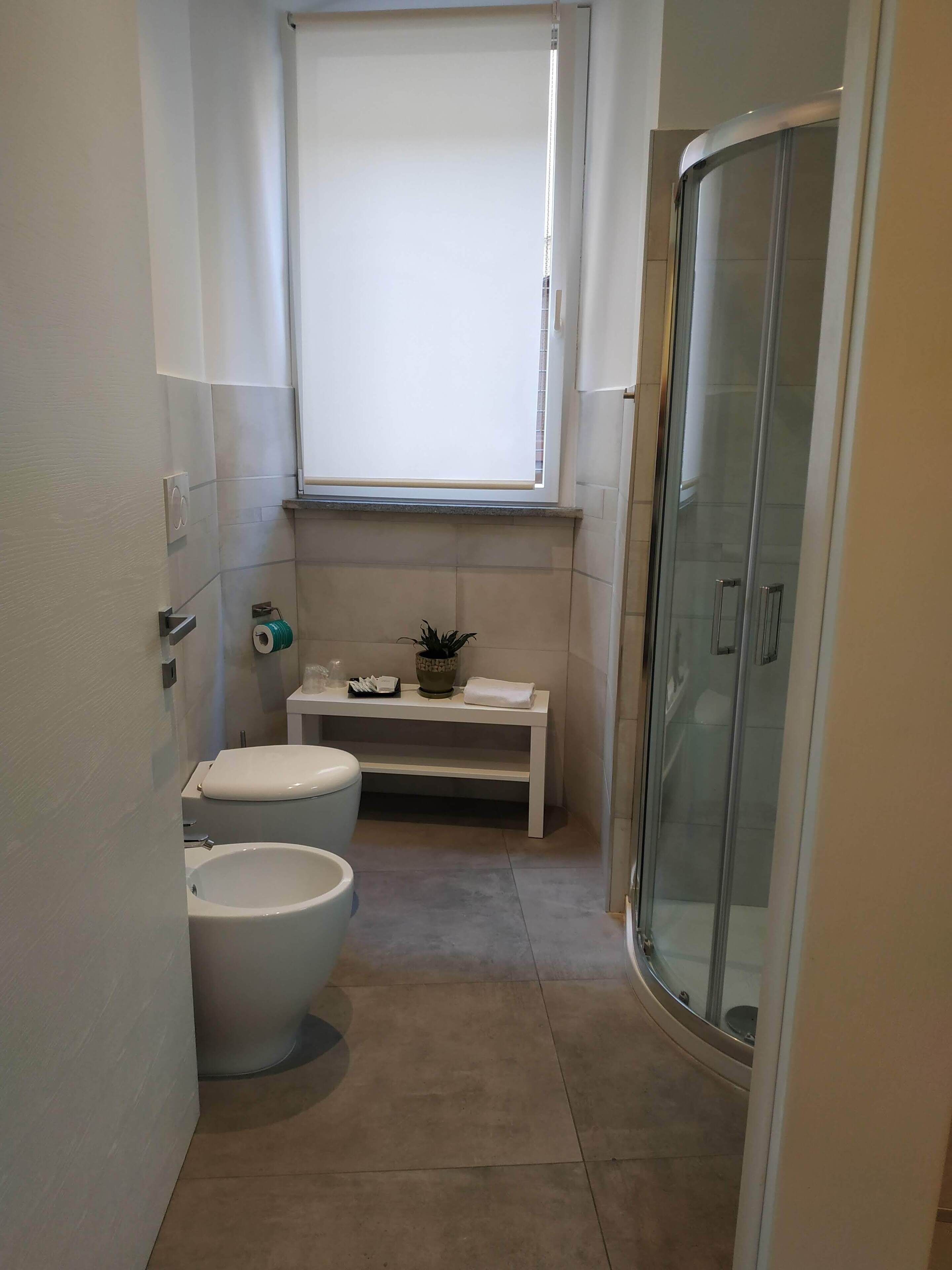 Un bagno con un water, un bidet e una cabina doccia in vetro.