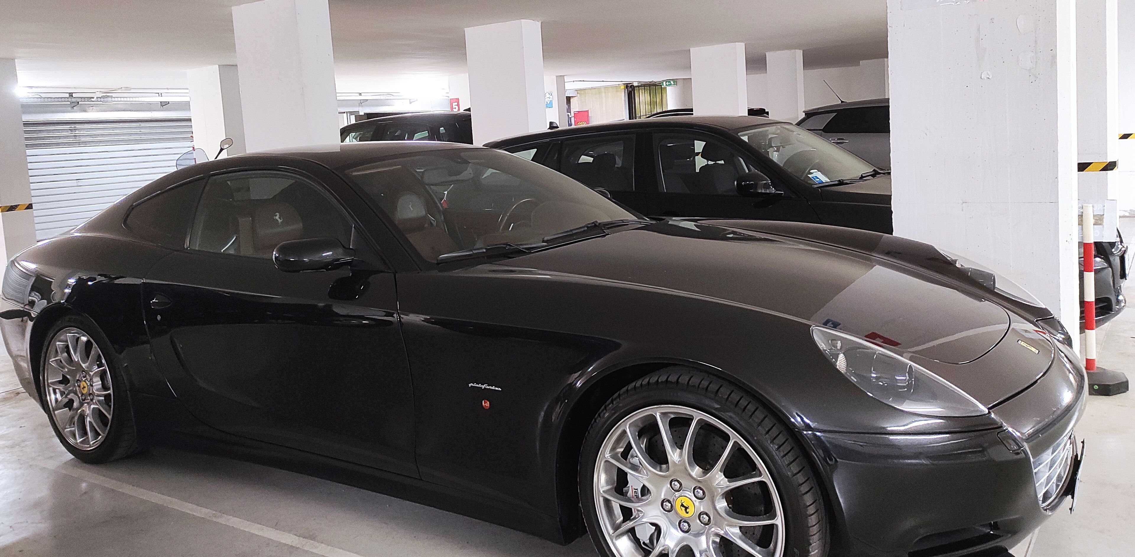 A black luxury car parked in a multi-level parking garage.