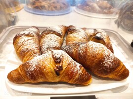 Una bandeja de cruasanes recién horneados espolvoreados con azúcar glas.