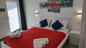 A hotel room with a bed, white nightstands, a window with curtains, and wall art. - Palazzo Verdi B&B (Viterbo)