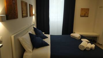 A hotel room with a bed, a bench, and artwork on the walls.