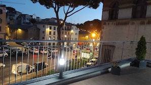 A balcony with a metal railing overlooking a street with parked cars and a building with multiple windows. - Palazzo Verdi B&B (Viterbo)