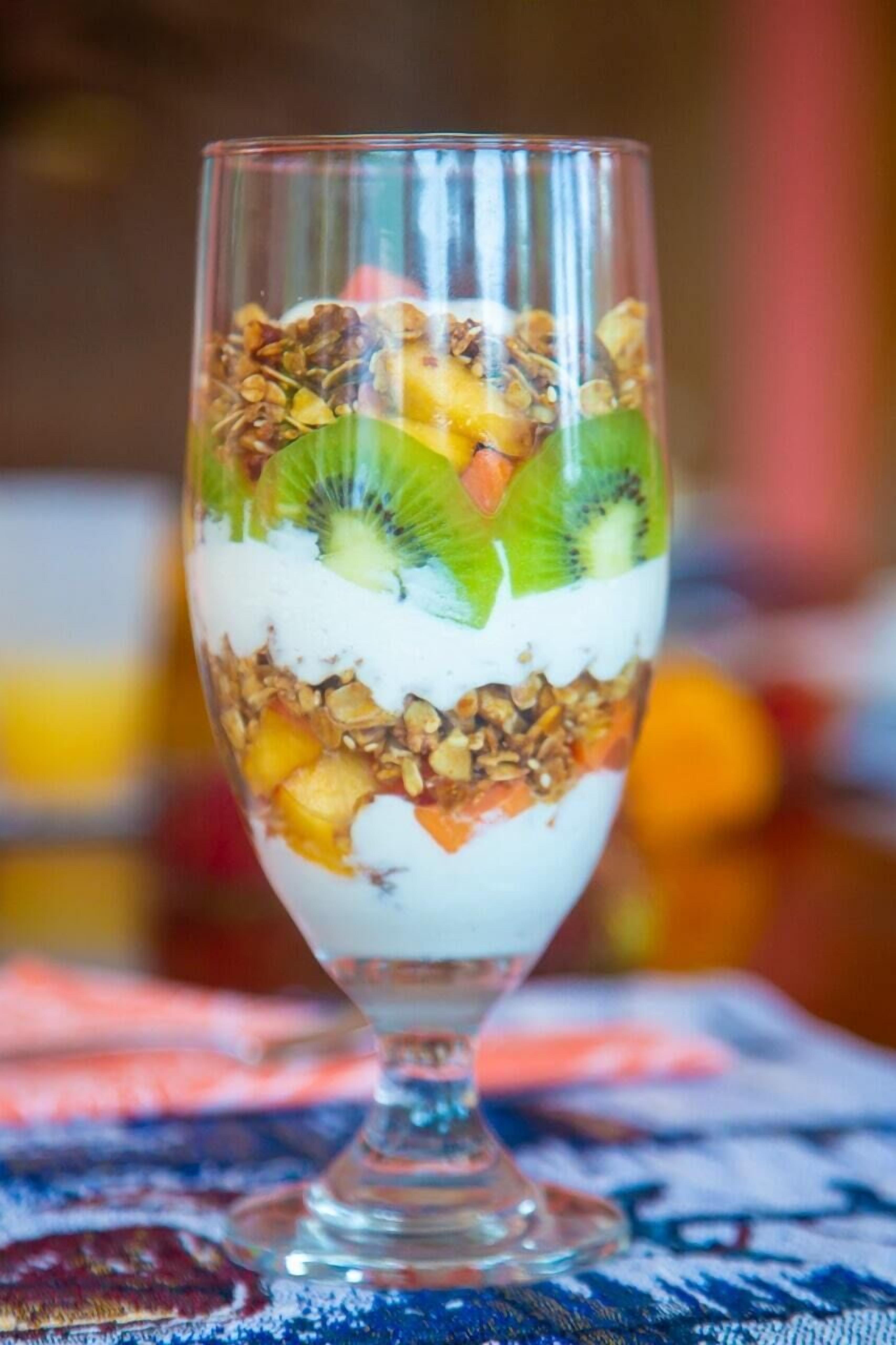 Ein Dessert im Glas mit Schichten aus Joghurt, Granola und Obst.