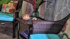 Une pièce meublée de meubles en osier, avec une plante décorative et une bougie posée sur une table.