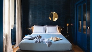 Une chambre à coucher avec un grand lit, un miroir rond au-dessus, et un plateau contenant divers objets posé sur le lit.